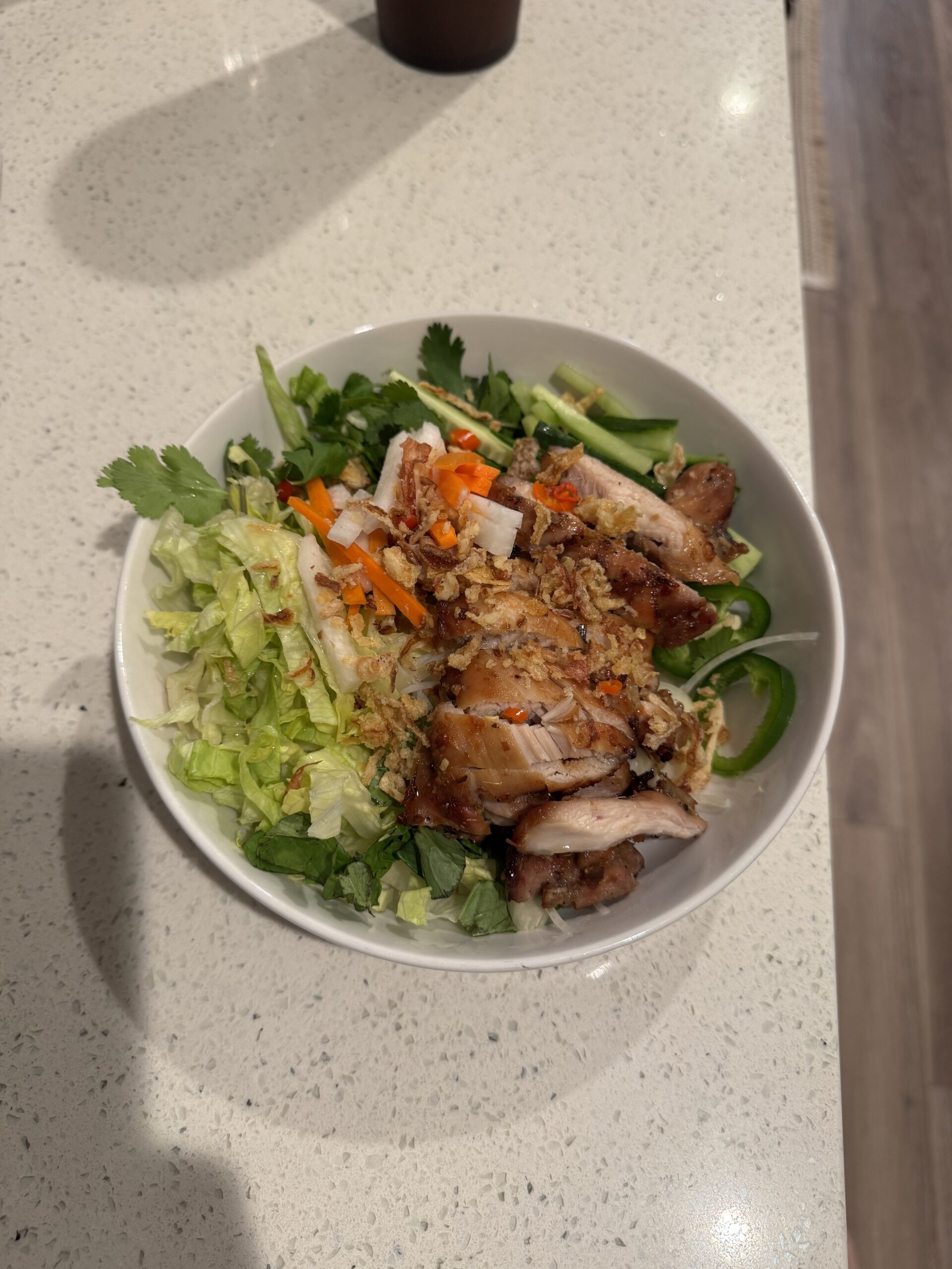 lemongrass grilled chicken over a bed of lettuce, cilantro, cucumbers