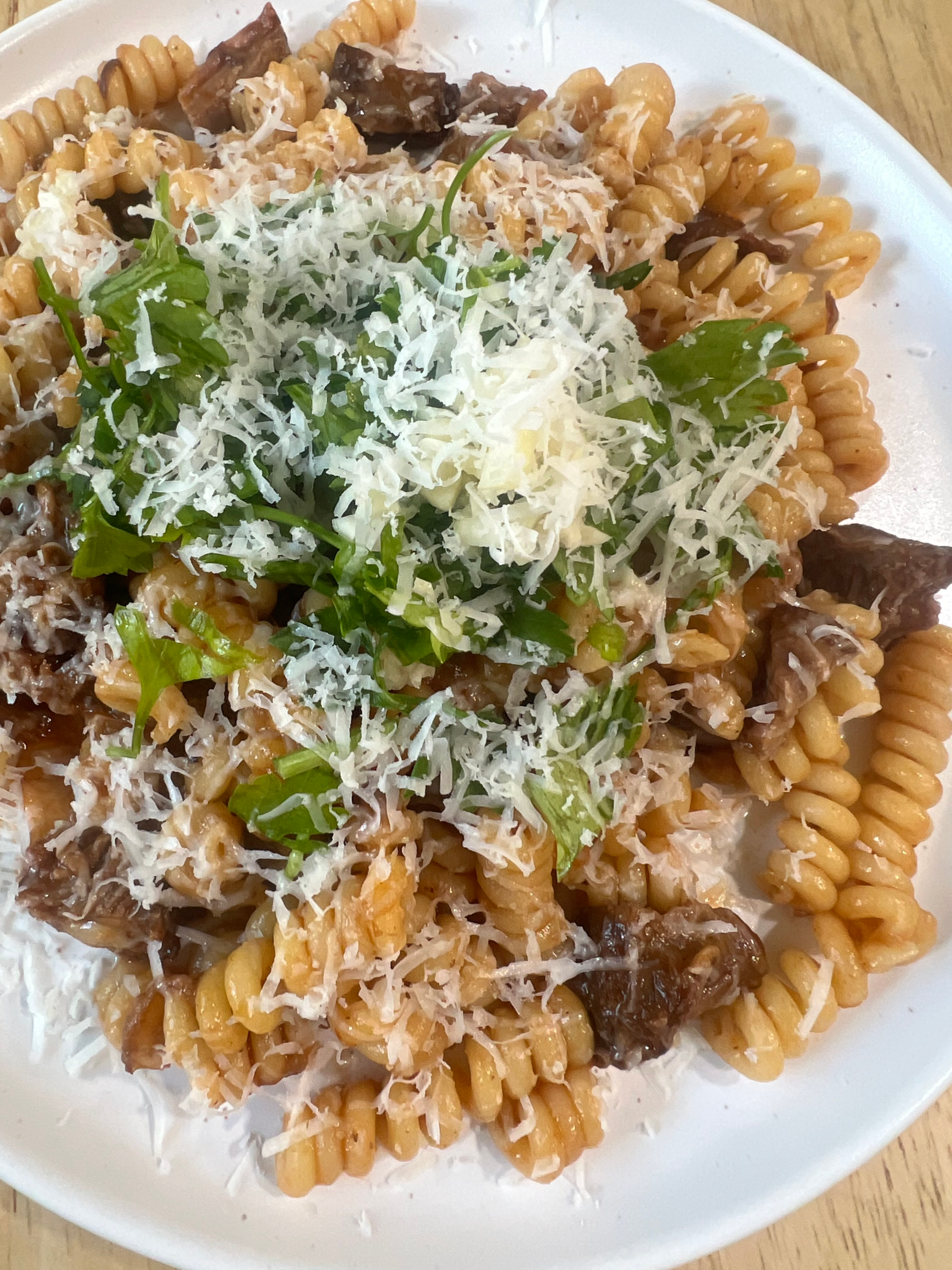 ossobuco with fusilli pasta topped with parsley and parmesan cheese